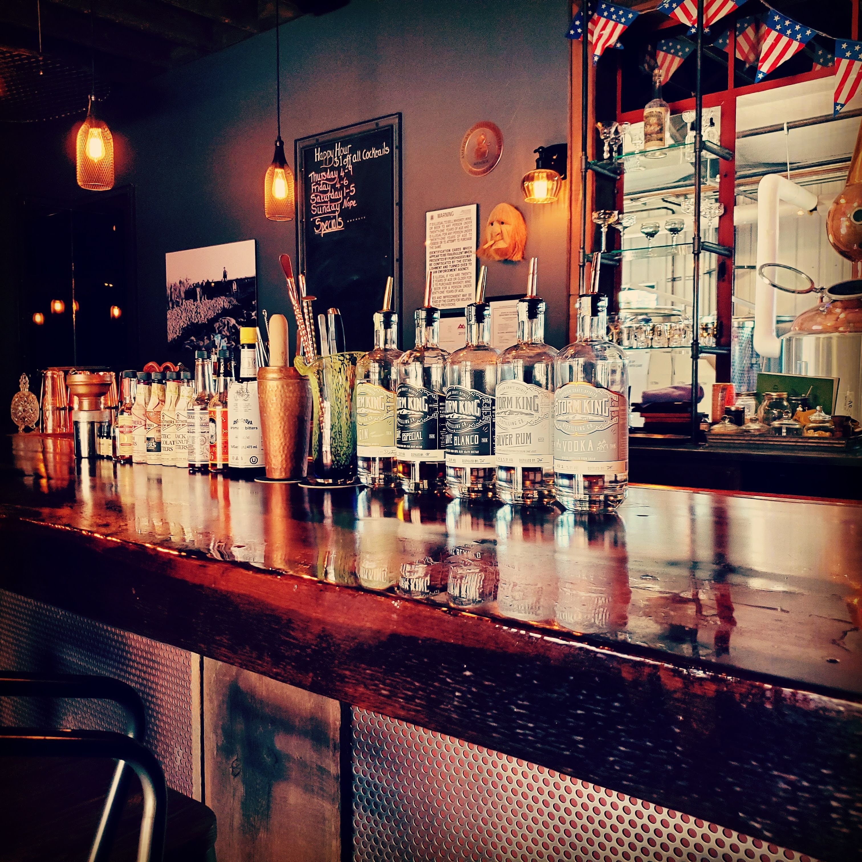 A bar with many bottles of alcohol on the counter.